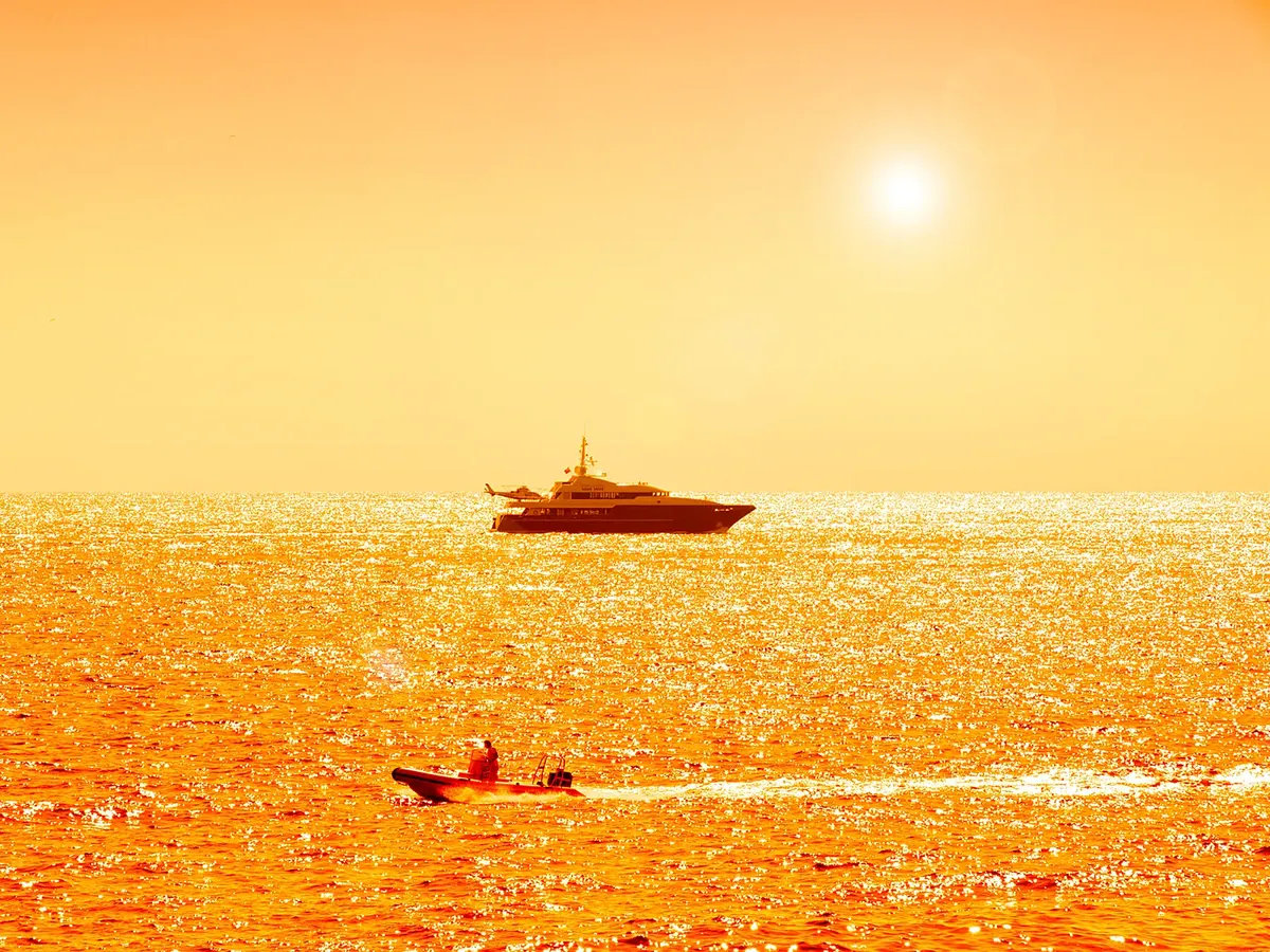 Yacht off Monaco at golden hour, the sea glittering in the backlight