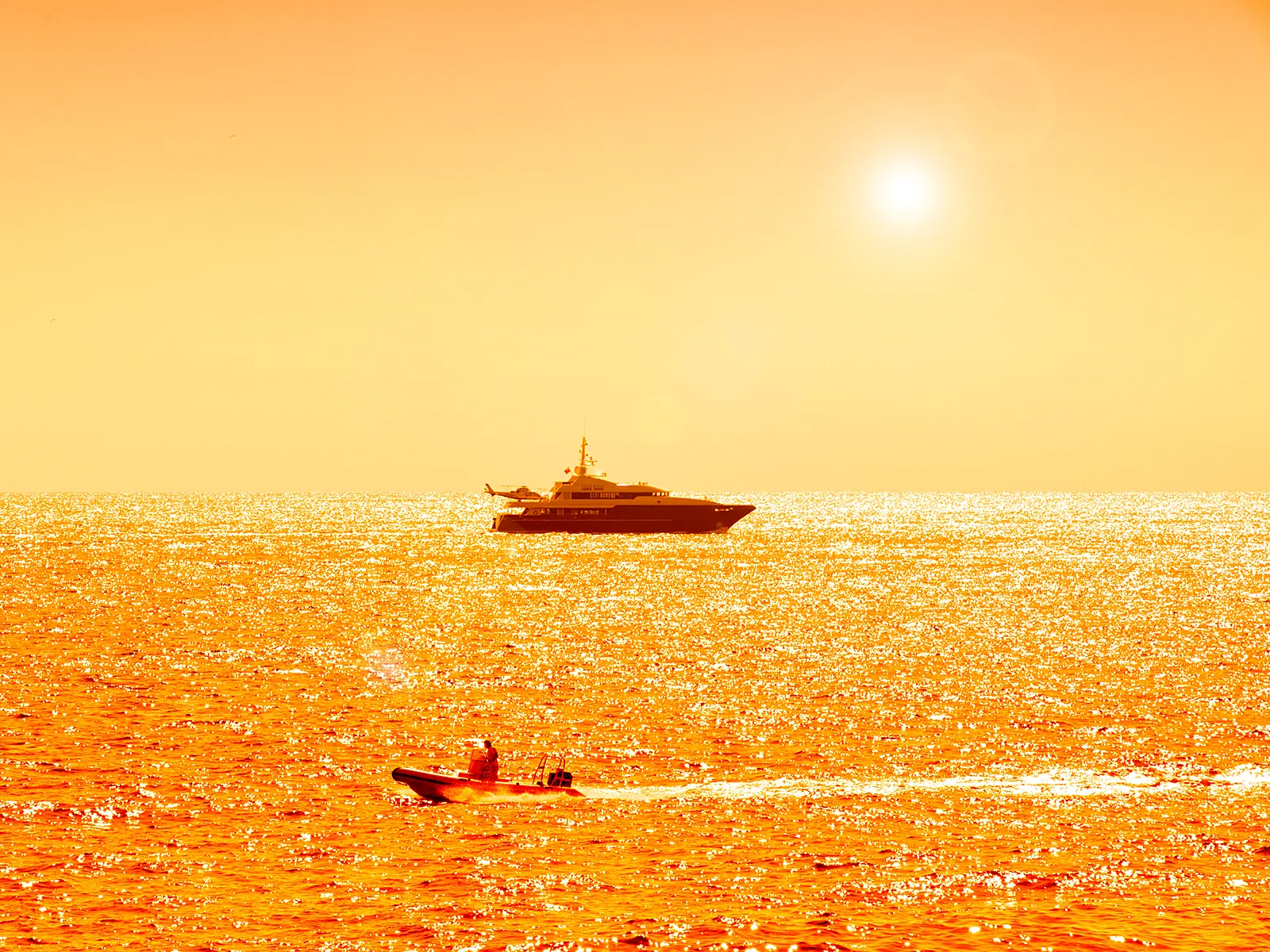 Superyacht off Monaco at golden hour, the sea glittering in the backlight